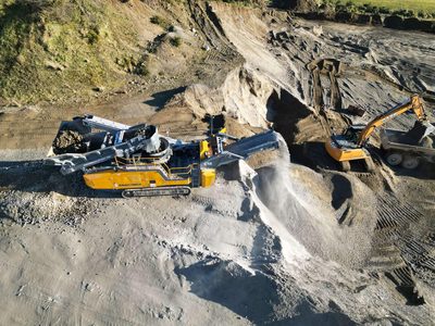 Anaconda C12 cone crusher working in a sand and gravel pit, an excavator loading a truck behind it