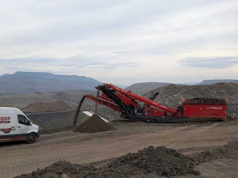The 2025 Finlay 684 two-deck screener stockpiling on a hillside job site, with a Skreenquip van parked in front